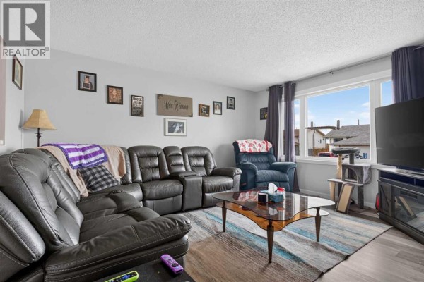 Living room with a dark leather sectional sofa, recliner chair, and large window. - 10004, 93 Ave, Wembley