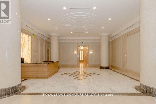 Apartment building lobby with marble floors, columns, and wooden reception desk. - 1001 - 36 Elm Drive W, Mississauga