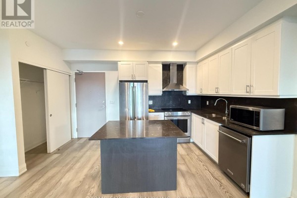 Kitchen with white cabinets, stainless steel appliances, and a dark grey island. - 1001 - 58 Lakeside Terrace, Barrie