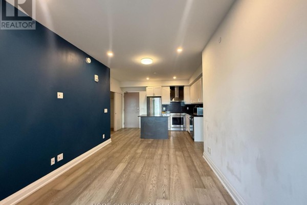 View of an open-concept living area and kitchen with light wood floors. - 1001 - 58 Lakeside Terrace, Barrie