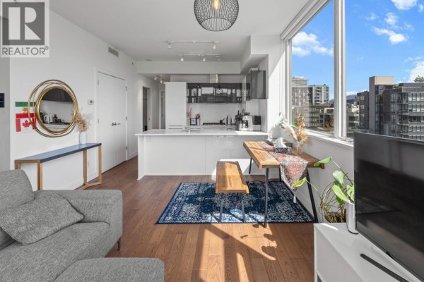 Modern white kitchen with a large island, stainless steel appliances, and dark grey upper cabinets. - 1001 108 E 1st Avenue, Vancouver