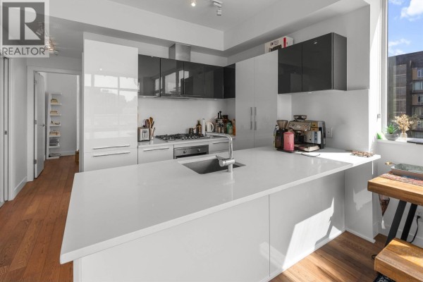 U-shaped modern kitchen with white high-gloss cabinets, stainless steel appliances, and hardwood floors. - 1001 108 E 1st Avenue, Vancouver
