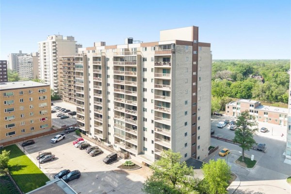 Aerial view of a 15-story apartment building with balconies and a parking lot. - 1001 246 Roslyn Road, Winnipeg