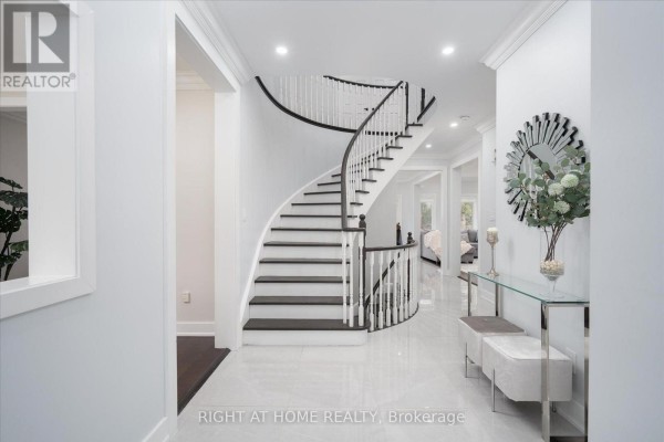 Foyer with a curved white staircase with dark treads and a glass console table. - 1001 Lytton Court, Pickering