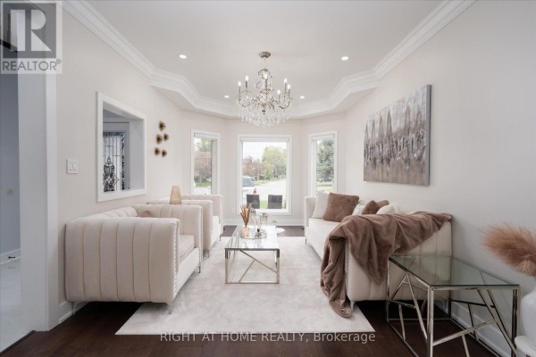 Living room with beige sofas, a glass coffee table, and a crystal chandelier. - 1001 Lytton Court, Pickering