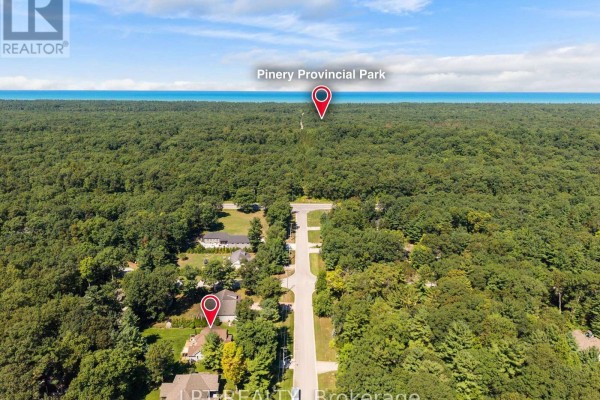 Aerial view of a suburban neighborhood surrounded by trees, showing proximity to Pinery Provincial Park and Lake Huron. - 10011 Jenna Road, Lambton Shores