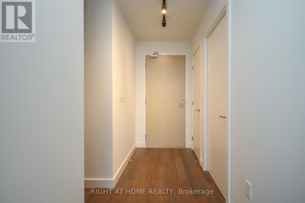 Interior view of a clean, white apartment hallway with dark wood floors. - 1002 - 224 Lyon Street, Ottawa