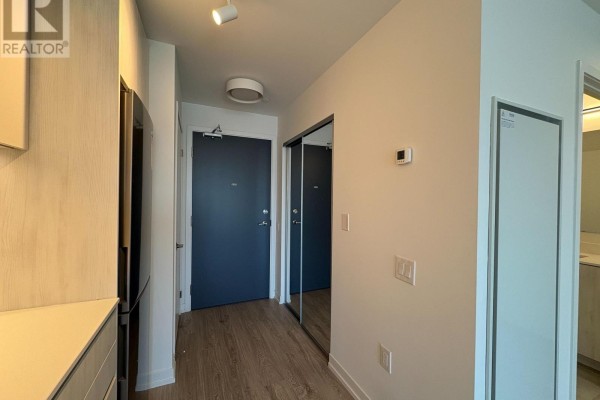 Apartment entrance hallway with light wood floors, neutral walls, and a mirrored closet door. - 1002 - 2485 Eglinton Avenue W, Mississauga