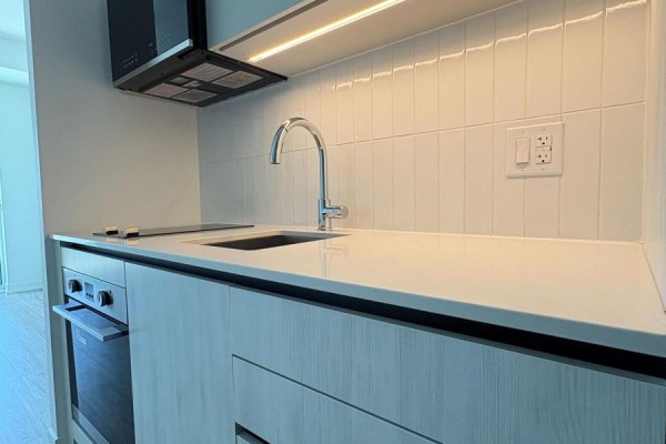 Close-up of the apartment kitchen counter with a modern faucet, sink, and white tiled backsplash. - 1002 - 2485 Eglinton Avenue W, Mississauga
