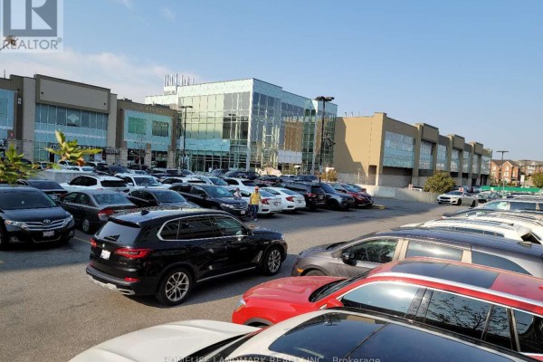 A full parking lot is visible in front of a commercial building with glass windows and beige siding. - 1002 - 32 South Unionville Avenue, Markham