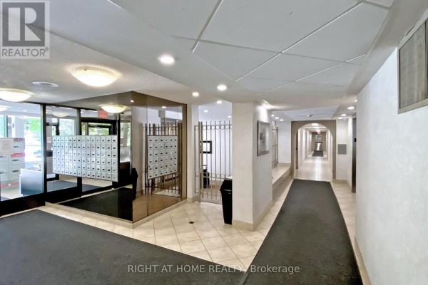 The building's lobby features mailboxes, tiled floors, and a long hallway with elevators. - 1002 - 40 Bay Mills Boulevard, Toronto