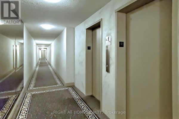 A long, narrow hallway in a condominium building with elevators and mirrored walls. - 1002 - 40 Bay Mills Boulevard, Toronto