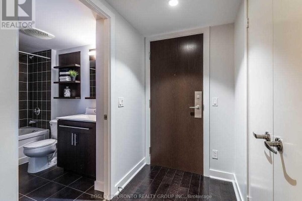 Apartment entryway with a dark wood door and a small bathroom visible. - 1002 - 80 Western Battery Road, Toronto