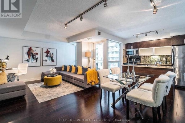 Open concept living, dining, and kitchen area with dark wood floors. - 1002 - 80 Western Battery Road, Toronto