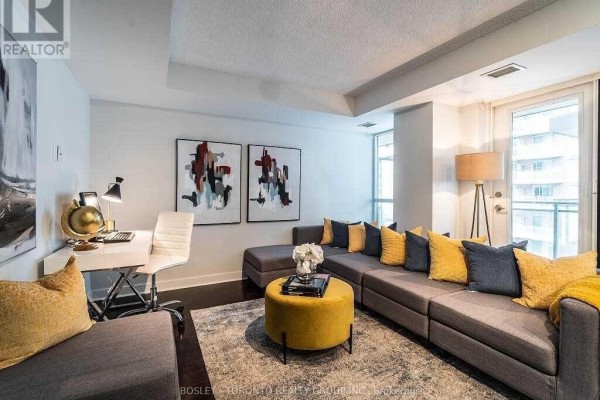 Living area with a sectional sofa, desk, and modern art on the walls. - 1002 - 80 Western Battery Road, Toronto