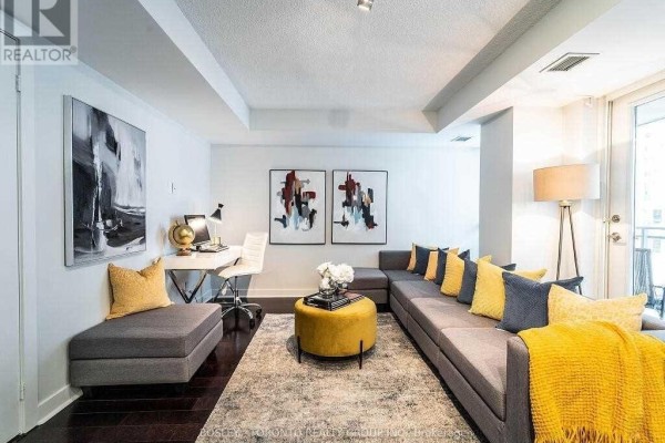 Living room featuring a sectional sofa, ottoman, and a home office area. - 1002 - 80 Western Battery Road, Toronto