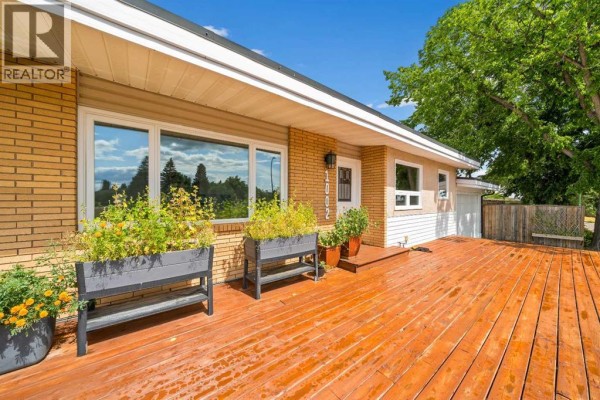 Wooden deck with planters in front of a beige and brick house. - 1002 13 Street Ne, Medicine Hat