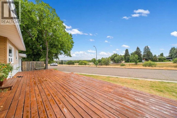 Wooden deck with views of a treed street and rolling hills. - 1002 13 Street Ne, Medicine Hat