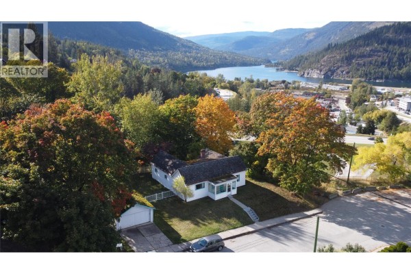 Aerial view of a white house with a lake and mountains in the background. - 1002 Kootenay Street, Nelson