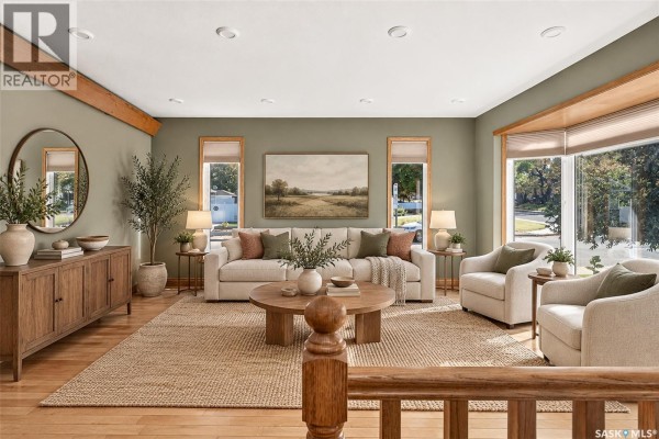 Living room with a sofa, two chairs, wooden buffet, and a bay window overlooking the street. - 1002 Vaughan Street, Moose Jaw