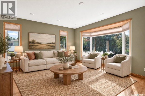 Living room with a sofa, chairs, round coffee table, and a large bay window with natural light. - 1002 Vaughan Street, Moose Jaw