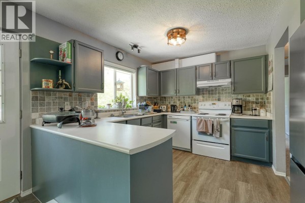 Gray kitchen with white countertops, stainless steel appliances, and light wood laminate flooring. - 10022 Rolley Crescent, Maple Ridge