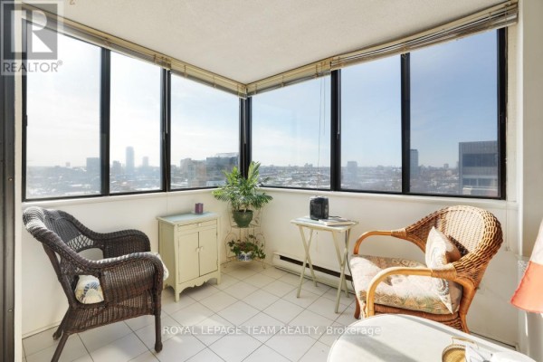 Enclosed sunroom with wicker chairs and city view - 1004 - 40 Arthur Street E Ottawa