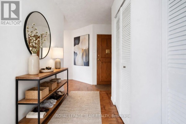 Hallway with console table, mirror, artwork, wood door, and closet - 1004 - 40 Arthur Street E Ottawa
