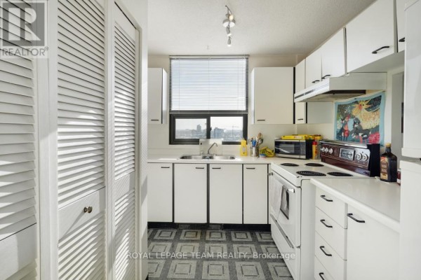 Kitchen with white cabinets, double sink, stove, microwave, and window view - 1004 - 40 Arthur Street E Ottawa