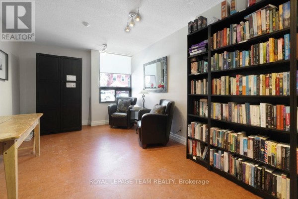 Living room with bookshelves, armchairs, and table - 1004 - 40 Arthur Street E Ottawa