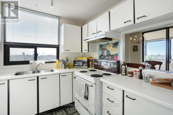 Kitchen with white cabinets, oven, microwave, and city view window - 1004 - 40 Arthur Street E Ottawa