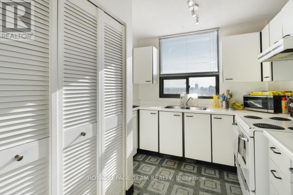 Kitchen with white cabinets, microwave, electric stove, louvered doors, and city view - 1004 - 40 Arthur Street E Ottawa
