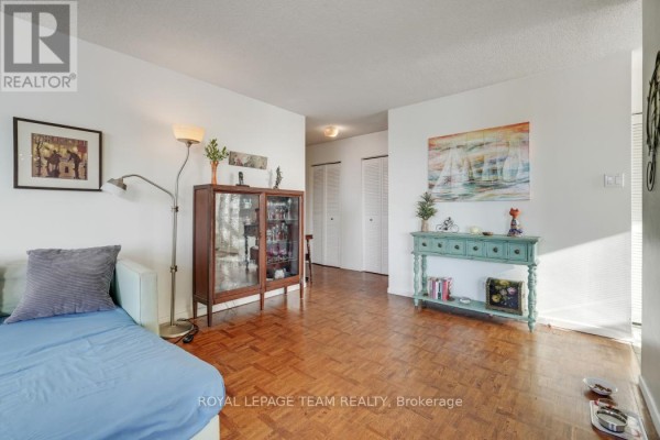 Living room with parquetry flooring, sofa, display cabinet, console table, and wall art - 1004 - 40 Arthur Street E Ottawa