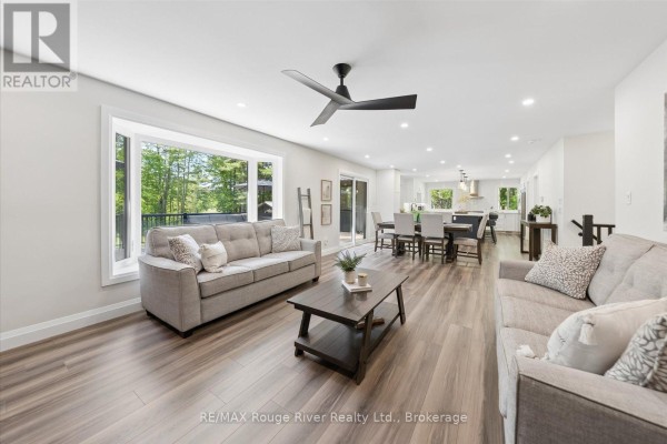 Bright kitchen featuring white cabinetry, stainless steel appliances, and a large island with seating. - 1004 Telecom Road, Kawartha Lakes