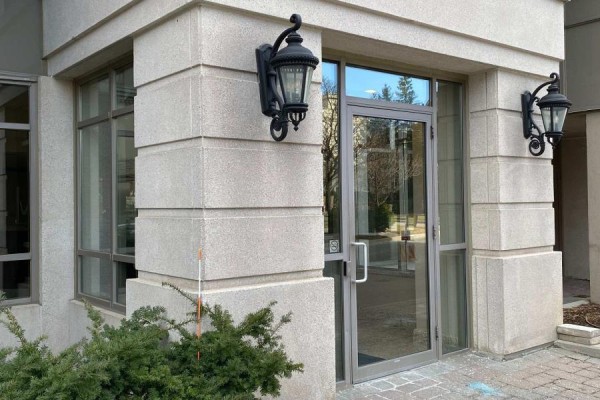 The building entrance features a glass door flanked by large stone blocks and outdoor lamps. - 1005 - 1 Clairtrell Road, Toronto