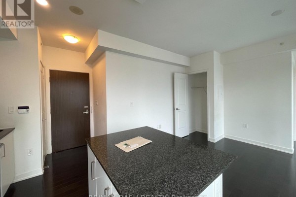 Kitchenette area with a dark granite island, dark wood floors, and white walls. - 1005 - 1 The Esplanade Drive, Toronto