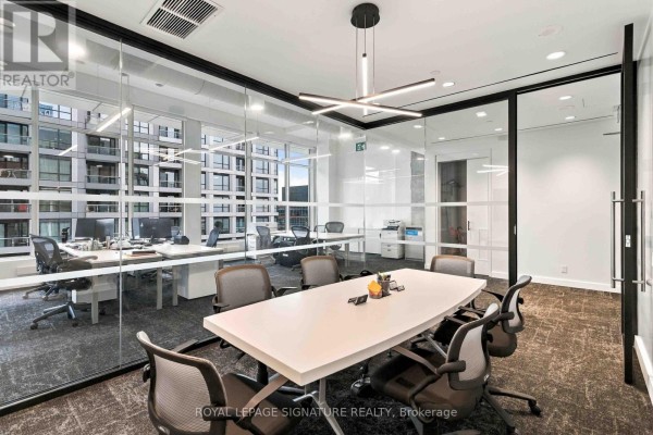 Conference room with a white table, black chairs, and glass walls showing the office space beyond. - 1005 - 130 Queens Quay E, Toronto