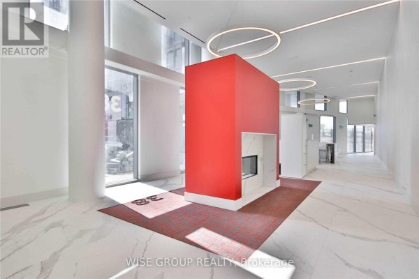 Modern lobby with a red central structure, marble floors, and circular light fixtures. - 1005 - 38 Monte Kwinter Court, Toronto