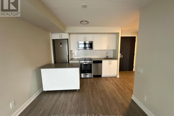 Apartment living area showing a compact kitchen with stainless steel appliances and island. - 1005 - 38 Monte Kwinter Court, Toronto