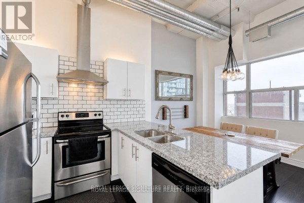 View of the kitchen island with granite countertops and a stainless steel sink, adjacent to the dining table. - 1005 - 700 King Street W, Toronto