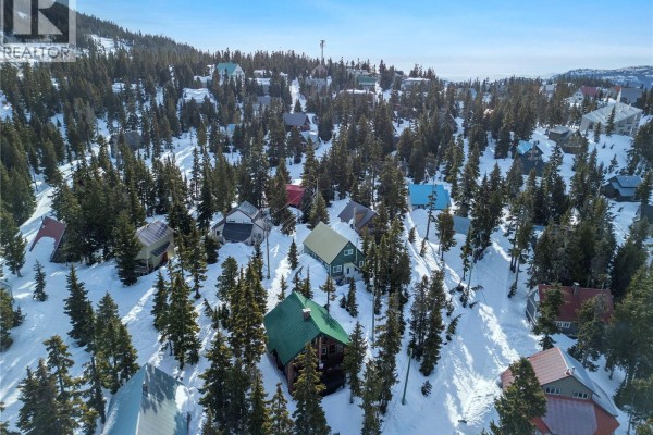 Aerial view of a wooded mountain community with colorful houses covered in snow. - 1005 Strata Way, Courtenay