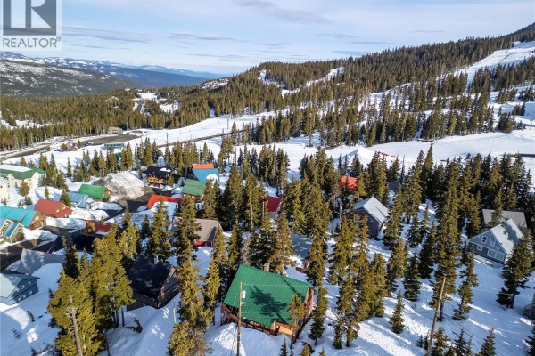 Panoramic aerial view of a mountain village with scattered houses amongst snow-covered trees and slopes. - 1005 Strata Way, Courtenay