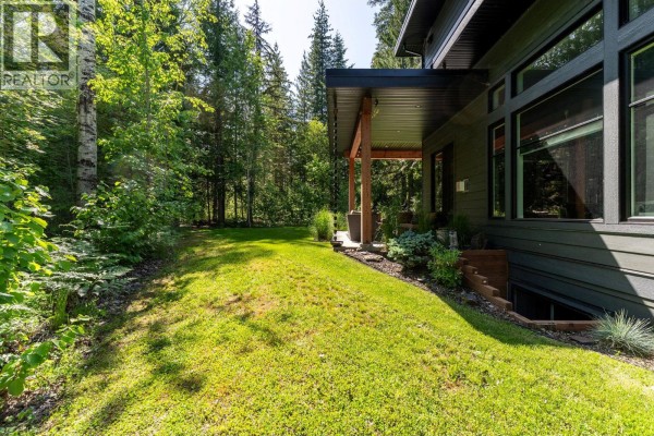 Side view showcasing landscaping, stone pathway, and covered area - 1005 Williams Gate Lane, Revelstoke