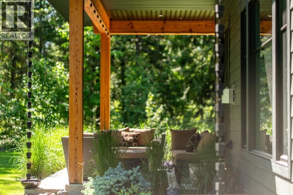Close-up of the covered patio with a storage area and greenery - 1005 Williams Gate Lane, Revelstoke