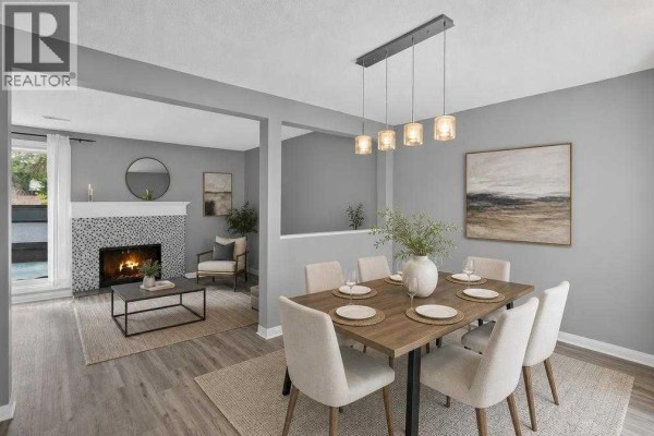 Dining area with a wooden table set for six, adjacent to a living room with a tiled fireplace. - 1006, 2520 Palliser Drive Sw, Calgary