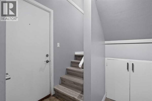 Interior view showing a white door, a small staircase with wooden steps, and a built-in cupboard. - 1006, 2520 Palliser Drive Sw, Calgary
