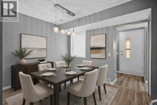 Dining room with a dark wooden table and chairs, sideboard, and wall art, facing the front entrance. - 1006, 2520 Palliser Drive Sw, Calgary