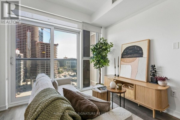 Modern open-concept kitchen and dining area with city view through floor-to-ceiling windows. - 1006 - 20 Richardson Street, Toronto