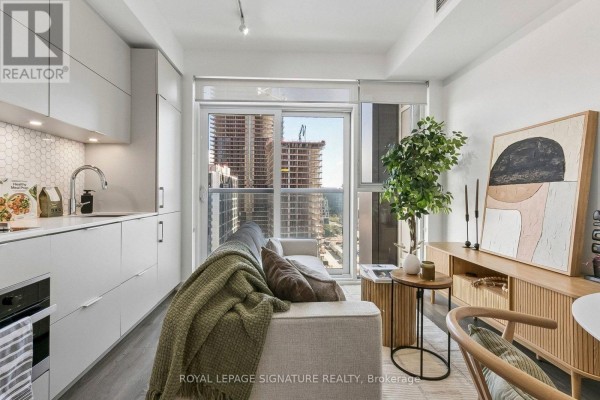 Living room with white sectional sofa, glass dining table, and abstract art. - 1006 - 20 Richardson Street, Toronto