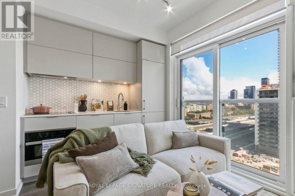 Bedroom with queen-size bed, bedside tables, and view of city skyline. - 1006 - 20 Richardson Street, Toronto